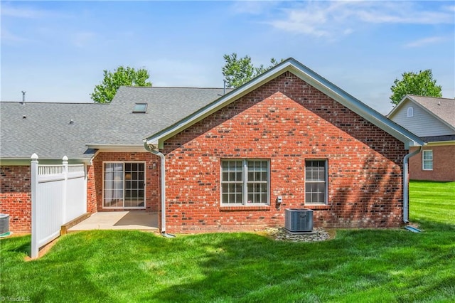 back of house with a lawn, central air condition unit, a patio area, and brick siding