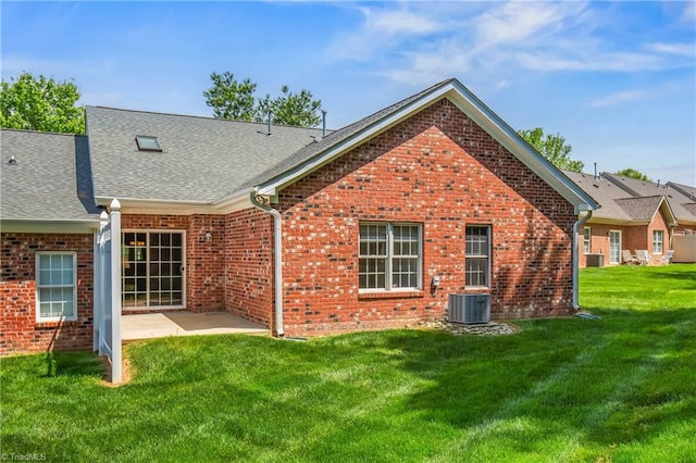back of property with roof with shingles, brick siding, cooling unit, a patio, and a yard