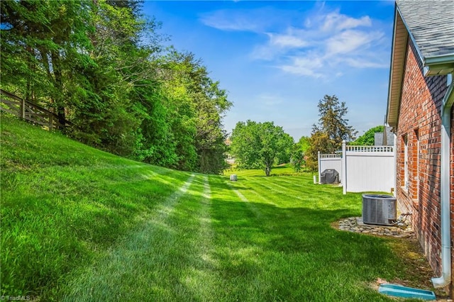 view of yard featuring central AC and fence