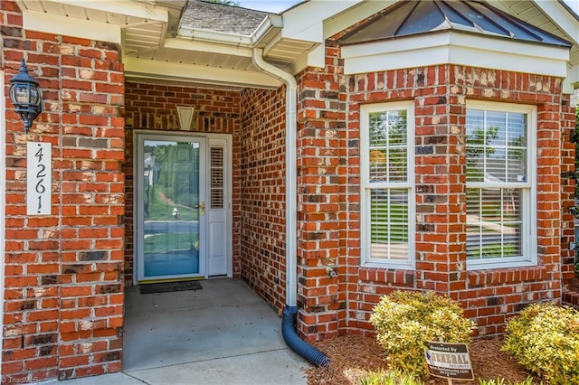 view of exterior entry featuring brick siding
