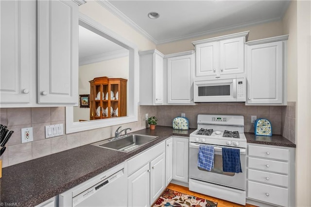 kitchen featuring a sink, dark countertops, white appliances, and white cabinetry