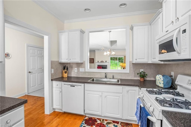 kitchen featuring a sink, dark countertops, light wood-style floors, and white appliances