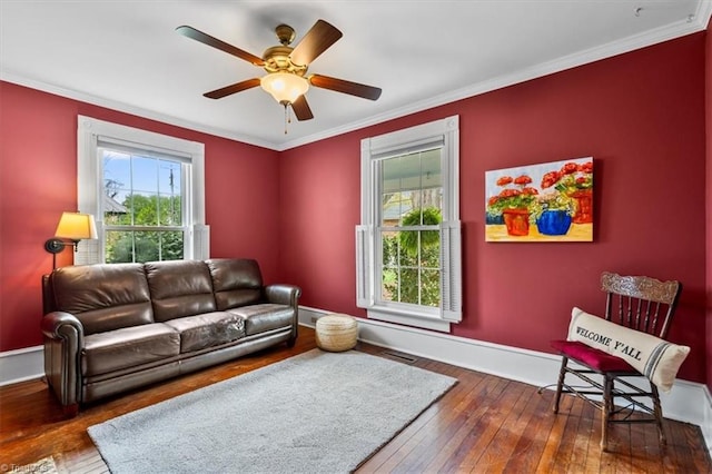 living area featuring plenty of natural light, visible vents, hardwood / wood-style flooring, and ornamental molding