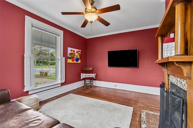 living area with crown molding, ceiling fan, a fireplace with flush hearth, wood finished floors, and baseboards