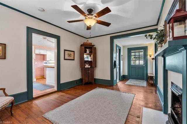 foyer entrance with wood finished floors, crown molding, and ceiling fan