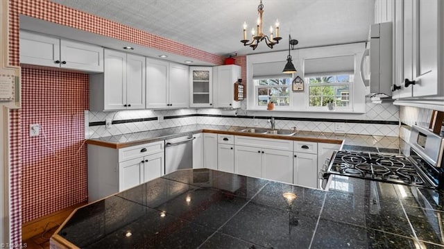 kitchen with a sink, decorative backsplash, an inviting chandelier, and stainless steel appliances