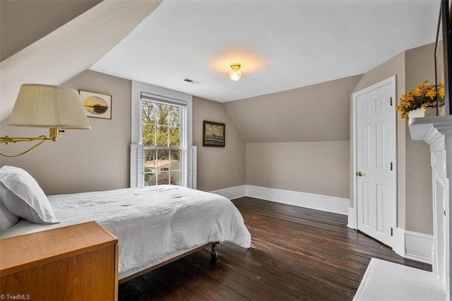 bedroom with baseboards, vaulted ceiling, visible vents, and hardwood / wood-style flooring