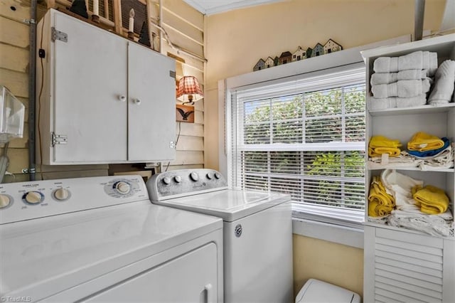 washroom featuring a healthy amount of sunlight, washing machine and clothes dryer, and cabinet space