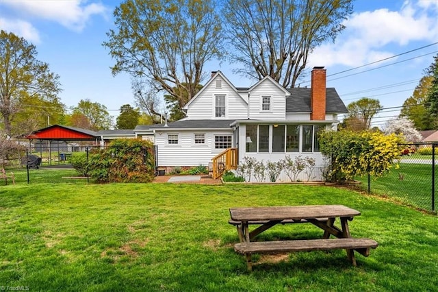 rear view of house with fence, a chimney, and a lawn