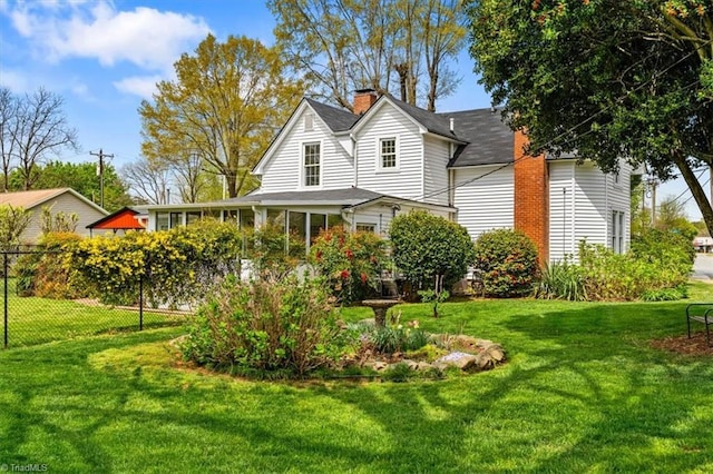 back of property featuring a sunroom, a yard, fence, and a chimney