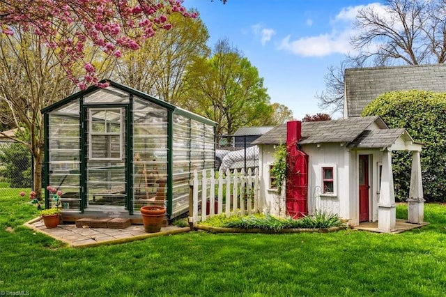 view of greenhouse featuring a yard and fence