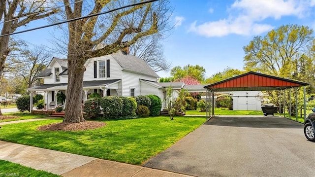 exterior space with an outdoor structure, a lawn, a detached carport, a porch, and driveway