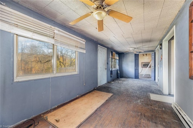 interior space with dark wood-type flooring, ceiling fan, and a baseboard heating unit