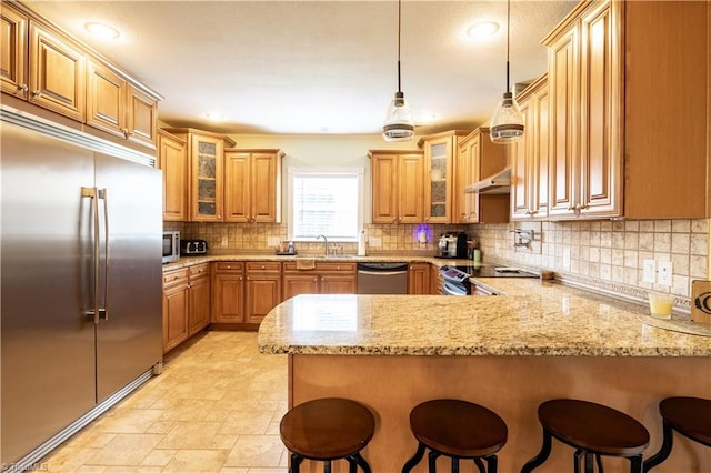 kitchen with light stone countertops, a kitchen bar, decorative backsplash, and stainless steel appliances