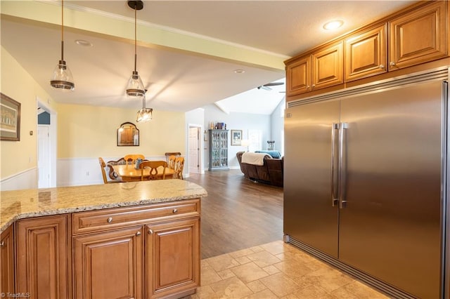 kitchen with stainless steel built in refrigerator, light wood-type flooring, light stone counters, pendant lighting, and vaulted ceiling