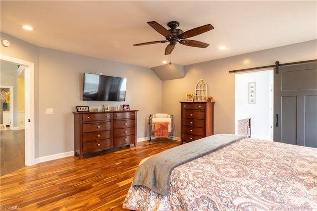 bedroom featuring a barn door, hardwood / wood-style flooring, and ceiling fan