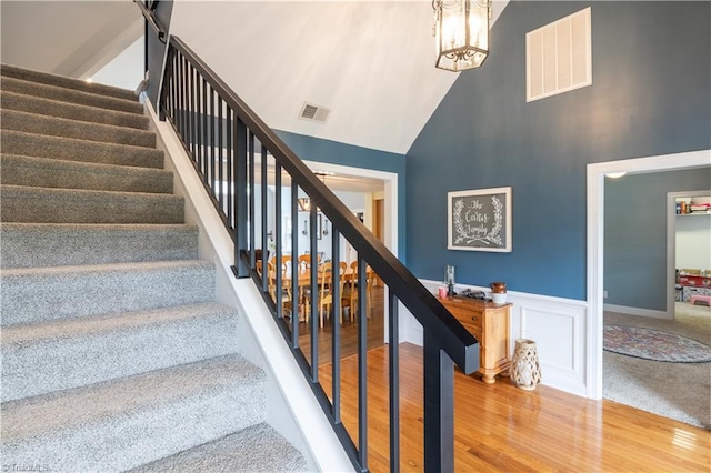 stairway with carpet floors and high vaulted ceiling