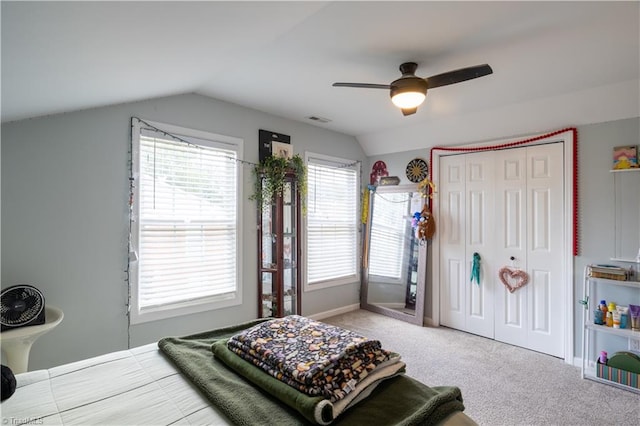 carpeted bedroom with ceiling fan, lofted ceiling, and a closet