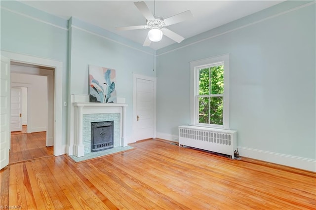 809 Simpson St, Greensboro, NC 27401 - unfurnished living room featuring radiator heating unit, light wood finished floors, a fireplace, a ceiling fan, and baseboards
