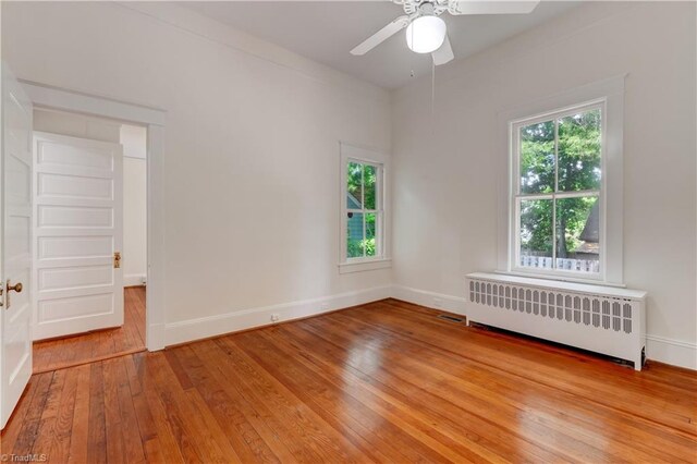809 Simpson St, Greensboro, NC 27401 - unfurnished room with radiator heating unit, light wood-style floors, ceiling fan, and baseboards