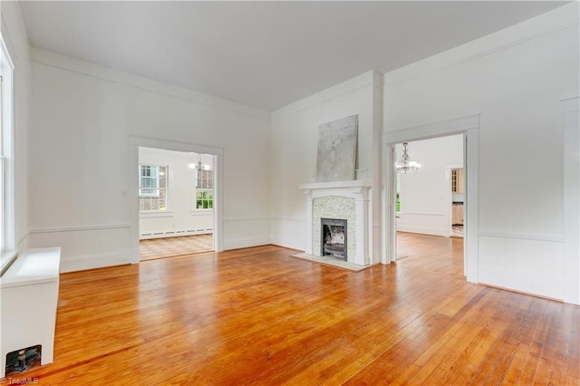 809 Simpson St, Greensboro, NC 27401 - unfurnished living room with baseboard heating, light wood-type flooring, a chandelier, ornamental molding, and a fireplace with flush hearth