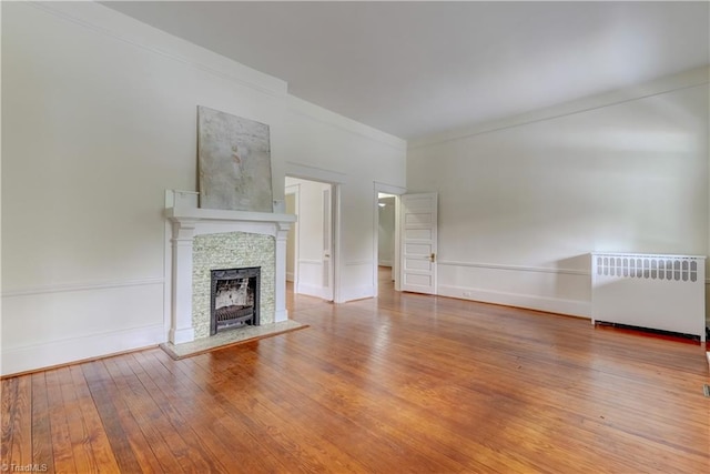 809 Simpson St, Greensboro, NC 27401 - unfurnished living room featuring radiator heating unit, ornamental molding, hardwood / wood-style flooring, a fireplace with raised hearth, and baseboards