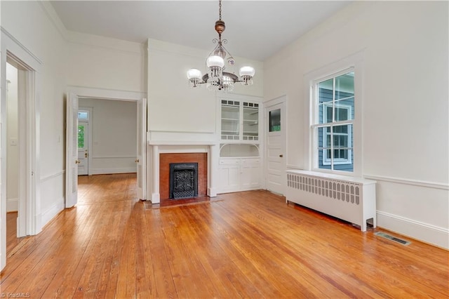 809 Simpson St, Greensboro, NC 27401 - unfurnished living room with radiator heating unit, a chandelier, healthy amount of natural light, and a fireplace