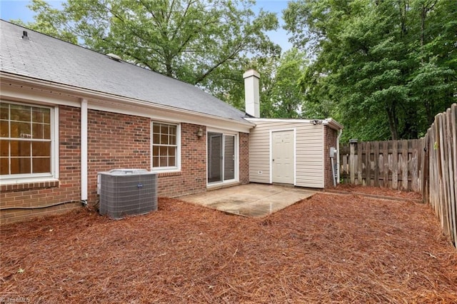 2704 Saint Johns Pl, Winston-Salem, NC 27106 - back of property featuring central AC unit, brick siding, a patio area, and a chimney