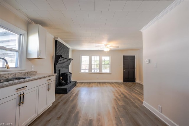 unfurnished living room with ornamental molding, a ceiling fan, a wealth of natural light, and a sink