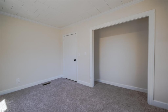 unfurnished bedroom with visible vents, baseboards, ornamental molding, and carpet flooring