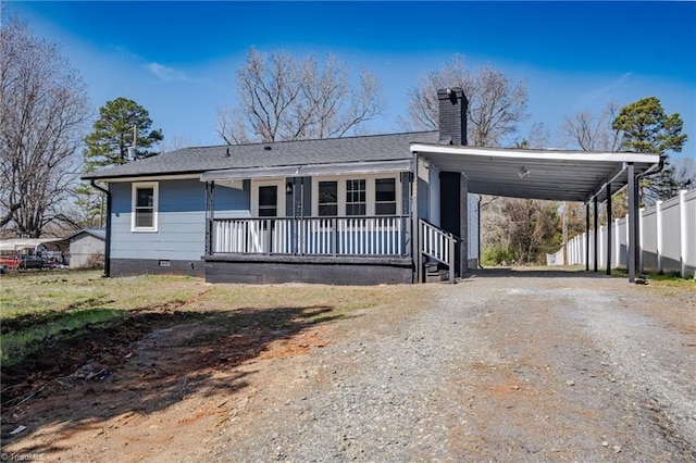 view of front of home with an attached carport, fence, driveway, a porch, and a chimney