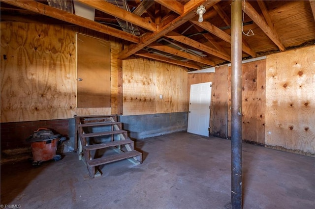 misc room with unfinished concrete floors and wood walls