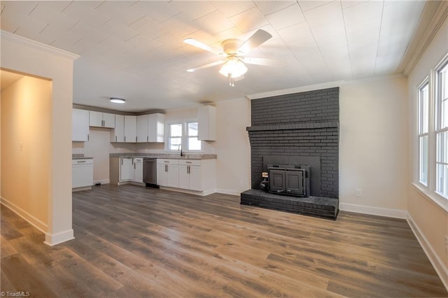 unfurnished living room featuring a sink, dark wood finished floors, crown molding, baseboards, and ceiling fan