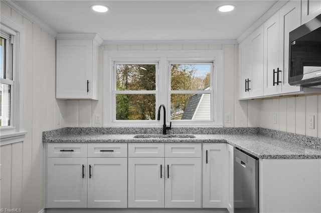 kitchen with white cabinets, stainless steel appliances, light stone counters, and sink