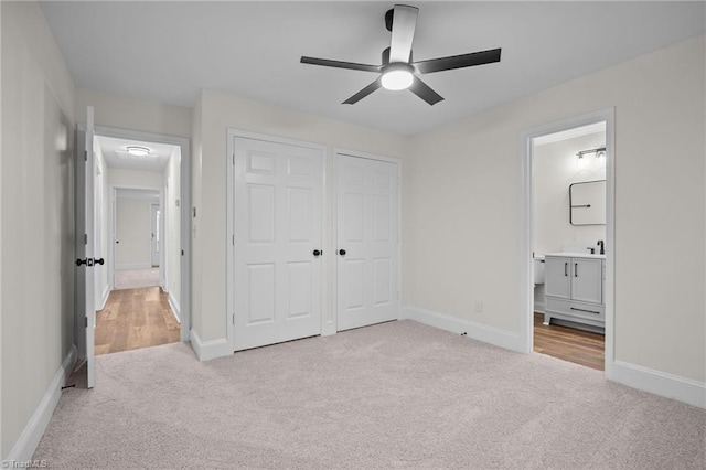 unfurnished bedroom with a closet, ensuite bathroom, ceiling fan, and light colored carpet