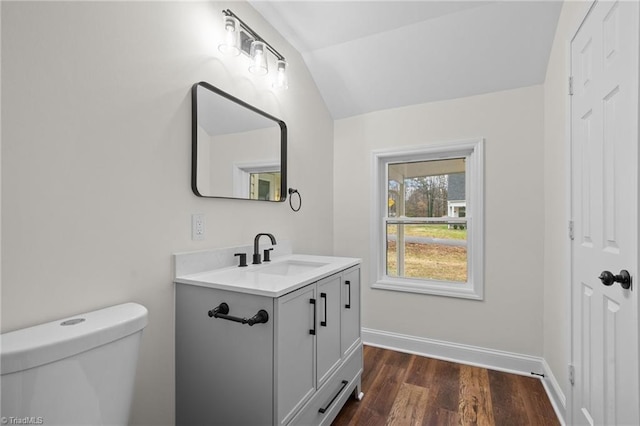 bathroom with wood-type flooring, vanity, toilet, and lofted ceiling