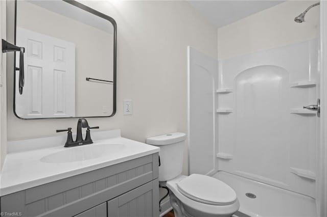 bathroom with toilet, a shower, and vanity