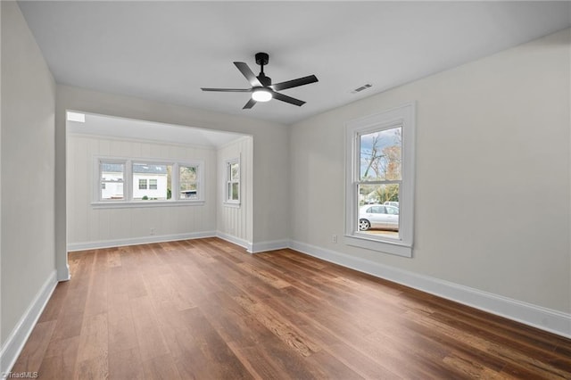 empty room featuring ceiling fan, wood-type flooring, and a wealth of natural light