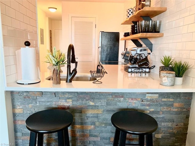 bar featuring refrigerator, tasteful backsplash, stainless steel range with electric cooktop, and sink