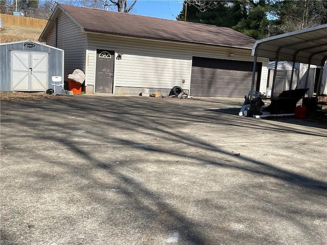 garage with a storage shed, driveway, and a carport