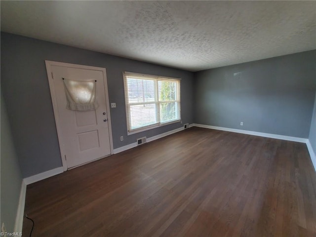 foyer entrance with dark wood finished floors, visible vents, a textured ceiling, and baseboards