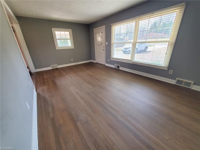 interior space featuring dark wood-type flooring, baseboards, and visible vents