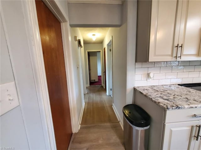 hall with light wood-style flooring and baseboards