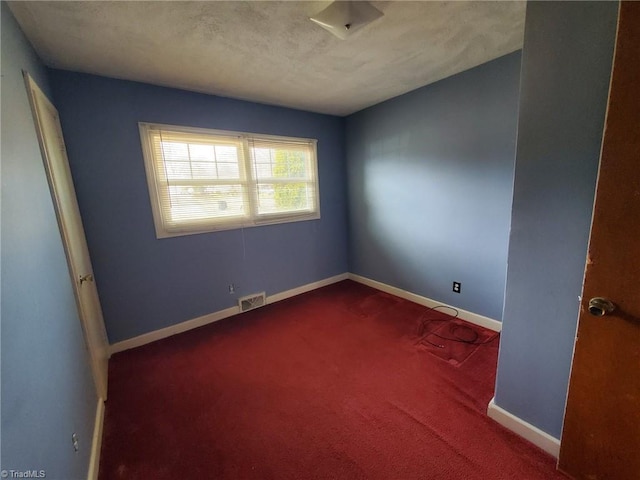 unfurnished room featuring visible vents, a textured ceiling, baseboards, and carpet floors