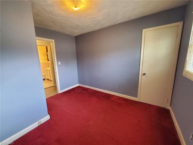 unfurnished room featuring a textured ceiling, baseboards, and carpet floors