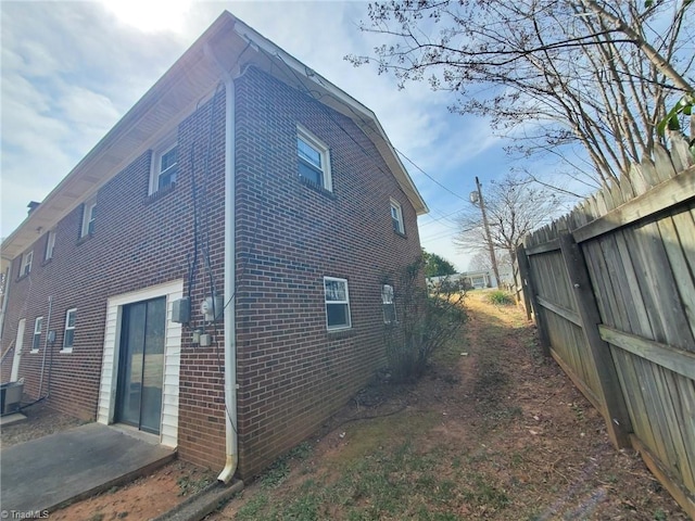 view of side of property with brick siding and fence