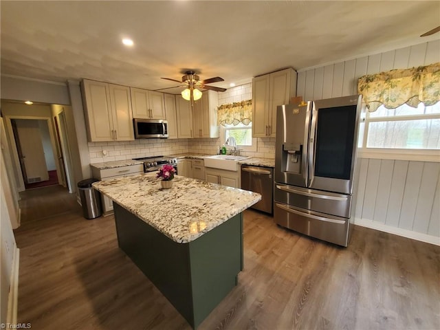 kitchen featuring a sink, tasteful backsplash, dark wood-style floors, a center island, and appliances with stainless steel finishes