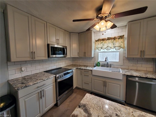 kitchen featuring decorative backsplash, wood finished floors, appliances with stainless steel finishes, and a sink