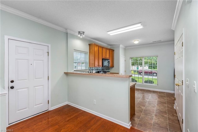 4339 Alderny Pl, High Point, NC 27265 - kitchen with black microwave, brown cabinetry, ornamental molding, a peninsula, and baseboards