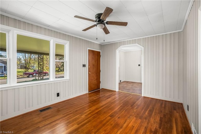 empty room with ornamental molding, ceiling fan, and dark wood-type flooring